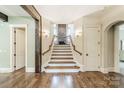 Elegant foyer with hardwood floors and a staircase featuring stone accents and decorative lighting at 157 Dedham Loop, Mooresville, NC 28117