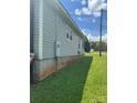 A side view of the house with light gray vinyl siding, a green lawn, and a clear blue sky at 206 13Th St, Belmont, NC 28012