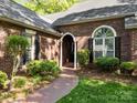Inviting brick home entrance with arched doorway, manicured shrubs, and a brick pathway at 617 Peace Haven Rd, Kannapolis, NC 28083