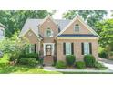 Charming brick home with mature landscaping, elegant arched windows, and black shutters for a sophisticated look at 11724 Brambleton Ct, Charlotte, NC 28277