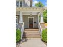 Inviting front porch with wood steps, white railing and columns, plus a stylish wooden door and well-maintained landscaping at 1241 Rollins Ave, Charlotte, NC 28205