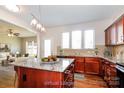 Virtual staged kitchen features an island with granite counters, wood cabinets and stainless steel appliances at 2327 Glenway Trail Ct, Pineville, NC 28134