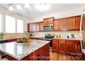 Virtual staged kitchen features a large island, stainless steel appliances, warm wood cabinets and tile backsplash at 2327 Glenway Trail Ct, Pineville, NC 28134