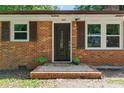 Close-up of front entrance with a dark door, brick facade, and decorative plants at 2401 Woodleaf Dr, Gastonia, NC 28052