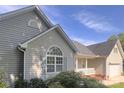 The exterior showing a large arched window, neutral vinyl siding, and a white columned front porch at 318 Linsbury Ct, Gastonia, NC 28056