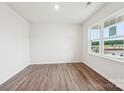 Sunlit bedroom with wood-look floors, white walls and a large window showcasing the outdoors at 4016 Cramer Estates Ct, Gastonia, NC 28056