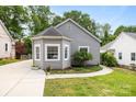 Charming gray home featuring a bay window, vinyl siding, manicured lawn and adjacent driveway at 509 W Sixth Ave, Gastonia, NC 28052