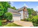 Attractive side view of home with brick and blue siding, well-kept lawn, mature tree, and a two-car garage at 5238 Downing Creek Dr, Charlotte, NC 28269