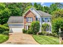 Inviting two-story home featuring brick and blue siding, a well-manicured lawn, mature trees, and an attached two-car garage at 5238 Downing Creek Dr, Charlotte, NC 28269