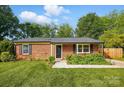 Charming brick home featuring a well-manicured lawn, mature trees, and a black front door at 529 Dedmon Dr, Charlotte, NC 28216