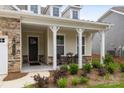 Inviting front porch features stone accents, white pillars, and cozy seating, enhancing the home's curb appeal at 7010 Brush Crk, Monroe, NC 28110