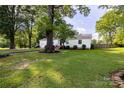 Single-story home featuring a lush green lawn, mature tree, and brick-lined garden bed at 80 Pine St, Badin, NC 28009