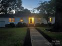 Exterior nighttime view of home featuring a welcoming front porch and a lit entry way at 80 Pine St, Badin, NC 28097