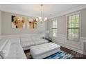 Elegant living room featuring a white sectional, ottoman, and two windows for natural light at 8347 Dallas Bay Rd, Charlotte, NC 28278