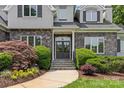 Elegant entrance featuring stone accents, a glass-paneled front door, and manicured landscaping at 9831 Sedgefield Dr, Waxhaw, NC 28173