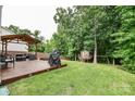 Spacious backyard featuring a wooden deck, covered seating area, and a ' playhouse with swings at 120 Tranquil Ct, Locust, NC 28097