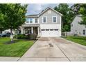 Two-story home with a two-car garage, well-manicured lawn, and a welcoming front porch at 120 Tranquil Ct, Locust, NC 28097
