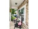 Cozy front porch with stone accents, rocking chairs with floral pillows, and potted plants at 120 Tranquil Ct, Locust, NC 28097