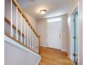 Inviting foyer with wood floors and staircase, featuring white door and light fixture at 15623 Sir Charles Pl, Charlotte, NC 28277