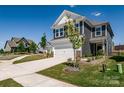 A sunny exterior view of a grey two-story home with a white garage and driveway at 16042 River Tree Ln, Charlotte, NC 28278