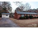 Brick home featuring a detached garage with a driveway and a neatly maintained lawn at 1708 Dogwood Ln, Lancaster, SC 29720