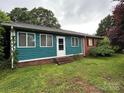 Charming single-story home with a brick foundation and teal siding, complemented by well-manicured landscaping at 2009 Hickory Grove Rd, Gastonia, NC 28056