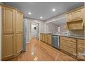 Well-lit kitchen features stainless steel appliances, granite countertops, and honey colored cabinetry with a wood floor at 201 Scalybark Trl, Concord, NC 28027