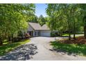 Inviting single-story home with lush greenery, a circular driveway, and attached two-car garage at 327 Wilby Dr, Charlotte, NC 28270