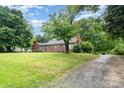 Traditional single-story brick home featuring mature trees and a well-kept lawn, exuding warmth at 3700 Nevin Rd, Charlotte, NC 28269