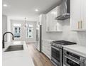 Modern kitchen with stainless steel appliances, white cabinets, quartz countertops, and wood flooring at 4011 Tundra Rd, Charlotte, NC 28203