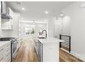 Open concept kitchen with island, stainless appliances, white cabinets, subway tile, and wood floors at 4011 Tundra Rd, Charlotte, NC 28203