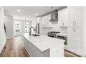 Modern kitchen with stainless steel appliances, white cabinets, quartz countertops, and wood flooring at 4011 Tundra Rd, Charlotte, NC 28203