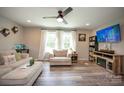 Comfortable living room with wood flooring, modern ceiling fan, and entertainment center at 407 Orchard Ln, Belmont, NC 28012