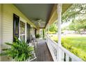 Cozy front porch with rocking chairs, ferns, ceiling fan, and classic railing perfect for relaxing outdoors at 503 New Castle Ne Ct, Concord, NC 28025