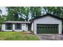 A charming single-story home with green door and garage, nestled among tall trees at 7228 Rollingridge Dr, Charlotte, NC 28211