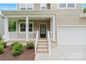 Inviting covered porch with white railing and pillars leads to the front door and attached two-car garage at 7308 Rothmore St, Charlotte, NC 28215