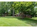 A beautiful brick home with a long driveway, surrounded by mature trees and lush green lawn at 915 Waterview Ln, Monroe, NC 28110