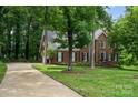 Beautiful brick home with a long driveway surrounded by lush greenery and mature trees at 915 Waterview Ln, Monroe, NC 28110