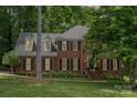 Charming two-story brick home with black shutters and a well-manicured lawn nestled among mature trees at 915 Waterview Ln, Monroe, NC 28110