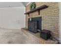 Close-up of a rustic brick fireplace with a wooden mantel and black iron stove insert at 94 Sumner Nw Ave, Concord, NC 28027
