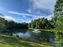 Scenic pond with a fountain surrounded by lush greenery and a blue sky at 9712 Worley Dr, Charlotte, NC 28215