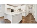 Bright kitchen features a large island, white cabinets, stainless steel appliances, and wood floors at 9924 Manor Vista Trl, Kannapolis, NC 28027