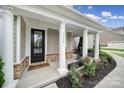 Inviting front porch features classic white columns, fresh flowers, and a cozy rocking chair, creating a welcoming entrance at 11216 Preservation Ln, Charlotte, NC 28278