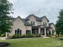 Stately two-story home boasts a well-manicured lawn and refined landscaping with a covered entryway and classic design at 1152 Grand Oak Dr, Waxhaw, NC 28173