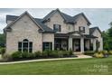 Charming brick home showcases a covered porch, symmetrical design, and verdant lawn enhancing its traditional appeal at 1152 Grand Oak Dr, Waxhaw, NC 28173