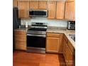 Galley kitchen features stainless steel appliances, warm wood cabinets, and granite countertops at 12238 Paperbark Cir, Charlotte, NC 28277