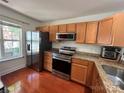 Well-equipped kitchen featuring wood cabinetry, granite countertops, and stainless steel appliances at 12238 Paperbark Cir, Charlotte, NC 28277