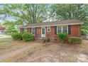 Quaint brick home with black shutters, green bushes, and a small front porch and yard at 1320 Hartford Ave, Charlotte, NC 28209