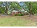 A home's rear exterior features mature trees and an expansive green lawn at 1320 Hartford Ave, Charlotte, NC 28209