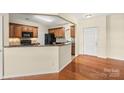 Eat-in kitchen boasts wood cabinets, granite countertops, black appliances, and hardwood floors extending to entry at 14853 Santa Lucia Dr, Charlotte, NC 28277